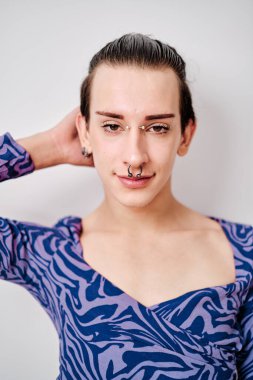 Modern eşcinsel bir adamın dikey portresi. Kameraya bakıyor ve poz veriyor.