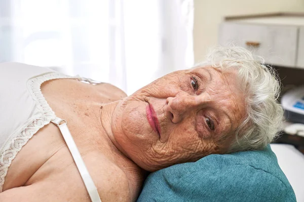 Close-up of the face of an elder woman lying on a clinic while receiving a massage