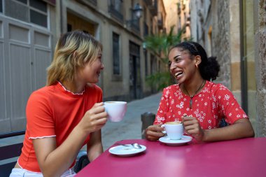 Çok kültürlü, rahat lezbiyen bir çift şehirde kahve içiyor.
