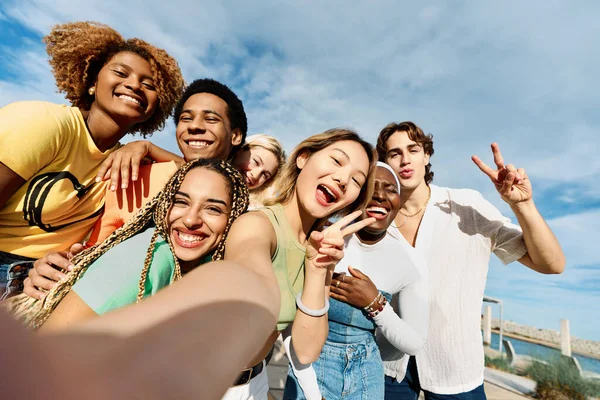 Chinese woman taking a selfie with multi-ethnic friends outdoors in a sunny day