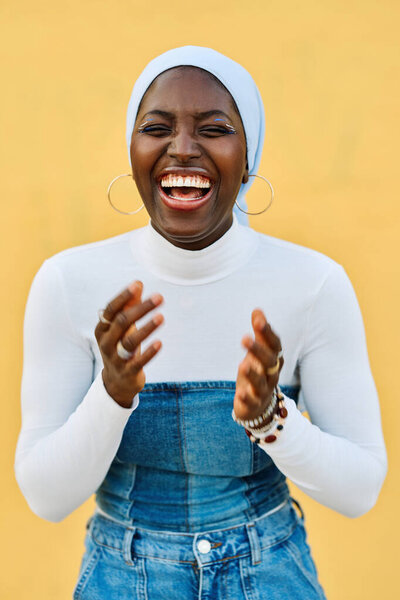Vertical portrait of an African muslim woman with hijab laughing happily