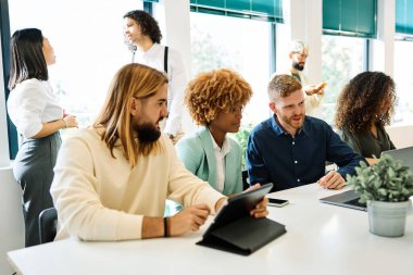 Ofiste dijital tablet kullanan genç ve çok ırklı çalışma ekibi