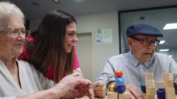 介護施設でスキルゲームをしながら笑顔で幸せな看護師や老人たちのビデオ — ストック動画
