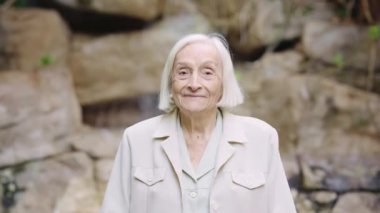Bir huzurevinde kameraya gülümseyen yaşlı bir kadının videosu.