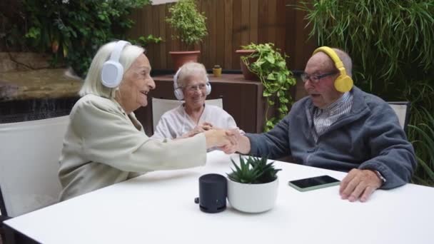 Видео Пожилых Людей Пожимающих Руки Время Прослушивания Подкаста Наушниками Доме — стоковое видео