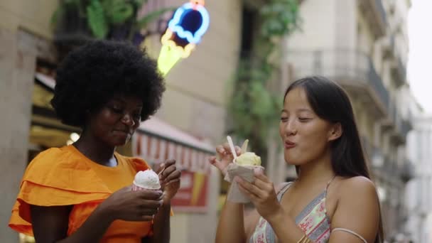 两个年轻的多种族朋友在巴塞罗那街头吃冰淇淋的视频 — 图库视频影像