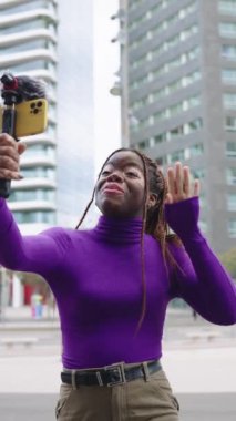 Vitiligo derili bir Afrikalı etkileyicinin şehirde cep telefonu önünde konuşurken dikey yavaş çekim videosu.