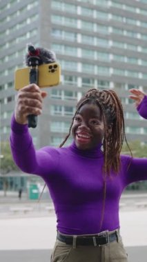Vitiligo ile şehirde telefon kullanan havalı bir Afrikalı kadının dikey yavaş çekim videosu.