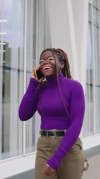 一个有着白垩风和辫子的非洲女人在城市里与流动电话交谈时的垂直慢镜头 — 图库视频影像
