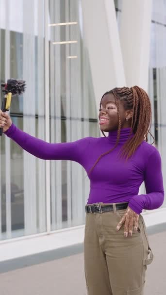 一个患有白垩风皮肤病的非洲博客的垂直慢镜头 在街上用电话记录了一个生活视频 — 图库视频影像