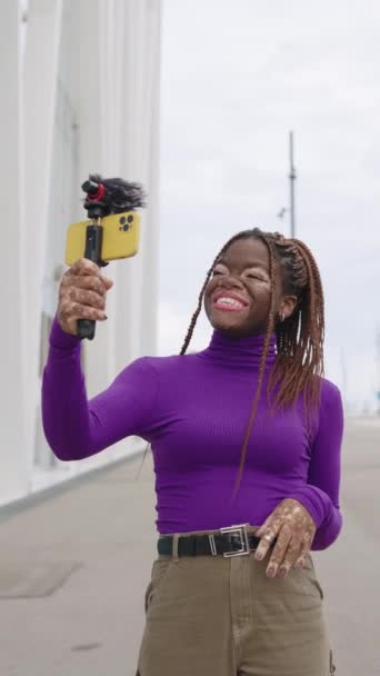 在城市里 一位年轻的有影响力的妇女带着白垩风的垂直慢动作视频用智能手机流媒体直播 — 图库视频影像
