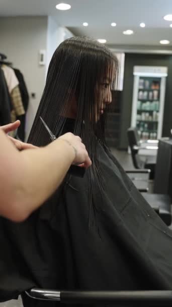 一位无法辨认的理发师耐心地将坐在美发厅里的一位中国女性顾客的头发剪下来 这是一个垂直的慢动作视频 — 图库视频影像