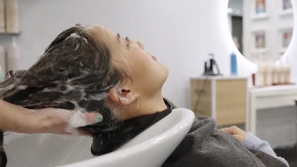 一名美发师在一家美容院的洗头槽前 为一位中国女性客户洗头的慢动作视频特写 — 图库视频影像
