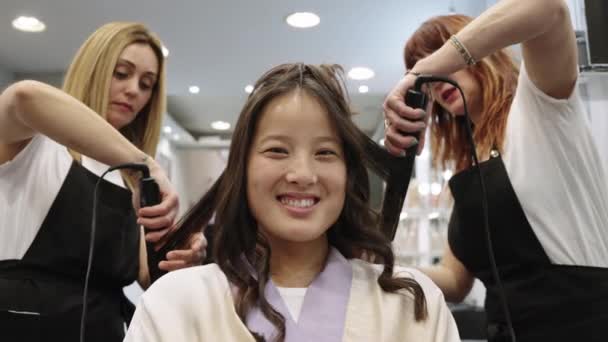 一个亚洲女人在美发店用扁平的熨斗卷头发时感到美丽的慢动作视频 — 图库视频影像
