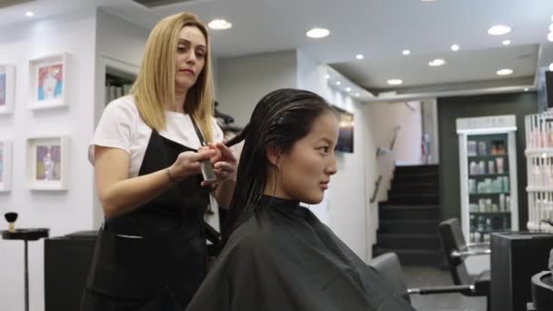 美容師のスローモーションビデオは サロンでそれをカットする中国の女の子の髪を収集します — ストック動画