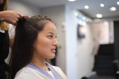 Çinli genç bir müşteri için örgü ören tanınmamış bir kuaförün yakın çekimi.