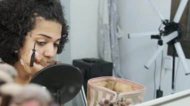Yavaş çekimde, banyoda oturmuş göz makyajı yapan transseksüel bir kadının videosunu kapat.