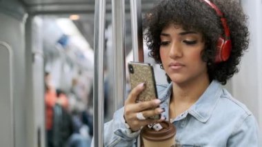 Bir trans kadının metroda elinde kahve tutarken cep telefonunu kullanmasının yavaş çekim videosu.