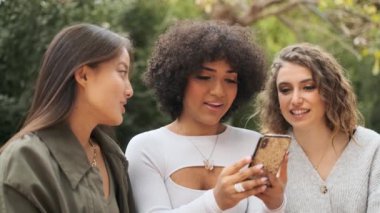 Bir grup kadın arkadaşın ve transseksüel bir kadının caddede birlikte cep telefonunu kullanmasının yavaş çekim videosu.