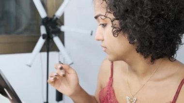 Bir transseksüel kadının masa aynası kullanarak göz farı sürerken yavaş çekim videosu.