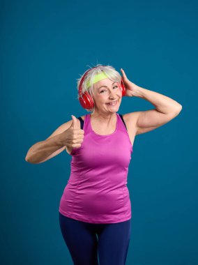 Parlak kırmızı kulaklıklı kıdemli fitness meraklısı.