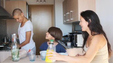 Lezbiyen bir çiftin ve ikiz olmayan bir çocuğun evde kahvaltı edişinin yavaş çekim videosu.