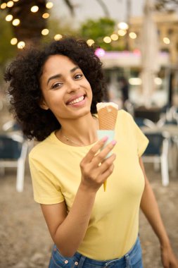 Gülümseyen Latin kadın dışarıda dondurma yiyor.