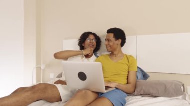 Eşcinsel çift yatak odalarında dizüstü bilgisayardan film seyrediyor.