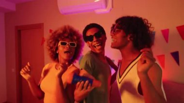 LGBTQIA arkadaşları renkli ışıklarla dans edip şarkı söylüyorlar.