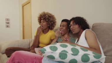 LGBTQIA arkadaşları patlamış mısır yiyor ve kanepede televizyon izliyorlar.