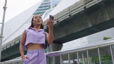 Genç transseksüel kadın Bangkok 'ta bir caddede akıllı telefonunu kullanıyor.