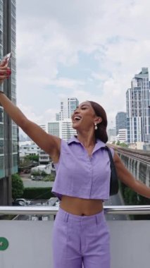 Genç kadın arka planda bangkoks silueti olan selfie 'ler için poz veriyor.