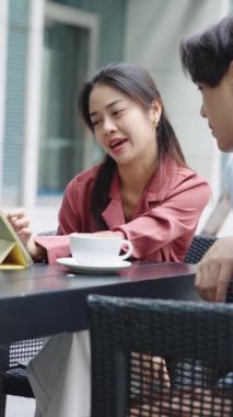İş kadını, Bangkok 'ta bir kafede kahve içerken bir iş adamına sunum yapmak için tablet kullanıyor.