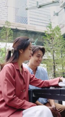 Genç çift bir masada oturuyor, kahve içiyor ve ağır çekimde konuşuyor.