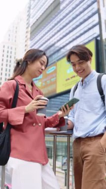 Genç bir adam ve kadın şehirde kahve molası veriyor. Ağır çekimde konuşan ve akıllı bir telefona bakıyor.