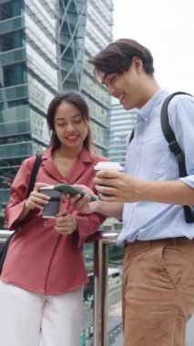 Bangkok 'ta kahve içerken akıllı telefona bakıp gülen genç bir çiftin yavaş çekim montajı.