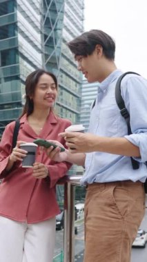 Genç bir adam ve kadın kahve molası veriyor, akıllı telefona bakıyor ve ağır çekimde konuşuyorlar.