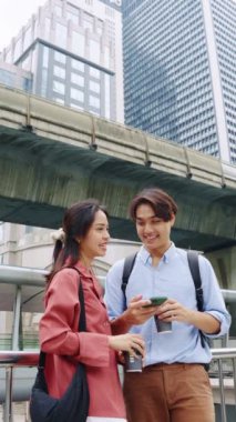 Genç çift akıllı telefon kullanıyor ve şehirde kahve içiyor.