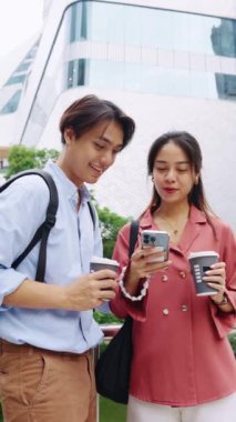 Genç çift Bangkok 'ta akıllı telefondan komik bir şey izliyor.