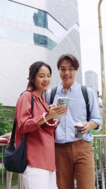 Genç çift Bangkok 'un hareketli sokaklarında dolaşmak için akıllı bir telefon kullanarak birlikte vakit geçirmekten zevk alıyor.