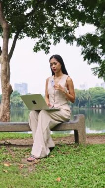 İş kadını parkta internetten alışveriş yaparken ağır çekim esintisinin tadını çıkarıyor.