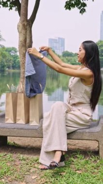 Alışveriş sonrası yeni kıyafetlerini gösteren genç bir kadının yavaş çekim sahnesi.