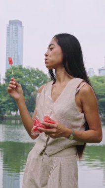 Bangkok parkında karpuz yiyen genç bir kadının yavaş çekim montajı.