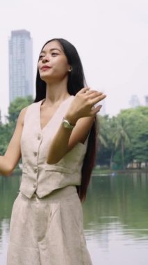 Bangkok 'ta bir parkta, kablosuz kulaklıklarıyla müzik dinleyen genç bir kadının yavaş çekim görüntüleri.