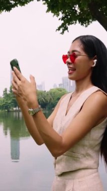 Kalp şeklinde güneş gözlüğü ve kulaklık takan genç bir kadın, müzik dinlerken güneşli bir günün tadını çıkarıyor.