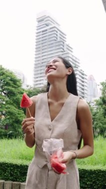 Genç iş kadını şehirde ferahlatıcı karpuz atıştırmalığının tadını çıkarıyor.