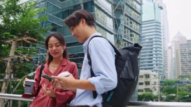 İki genç profesyonel kahve molası veriyor ve modern bir şehir ortamında akıllı telefon kullanıyorlar.