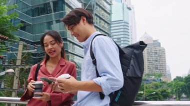 İki genç girişimci Bangkok sokaklarında akıllı bir telefona bakarken sohbet ediyorlar.