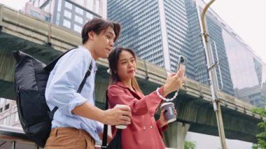 Genç turistler Bangkok 'ta canlı bir şehir ortamında neşe ve bağlantılarını gösteren akıllı bir telefonla selfie çekiyor.