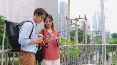 Genç turistler birlikte vakit geçiriyorlar, akıllı telefon kullanıyorlar ve canlı bir şehir ortamında kahve fincanları tutuyorlar.